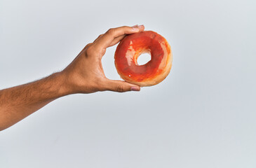 Wall Mural - Hand of hispanic man holding donut over isolated white background.