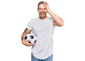 Wall Mural - Young irish man holding soccer ball smiling happy doing ok sign with hand on eye looking through fingers