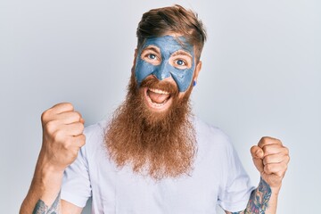 Canvas Print - Young irish redhead man wearing facial mask screaming proud, celebrating victory and success very excited with raised arms