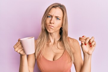 Poster - Beautiful caucasian woman drinking coffee and eating french pastry macaron skeptic and nervous, frowning upset because of problem. negative person.