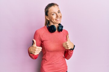 Wall Mural - Beautiful caucasian woman wearing sportswear and arm band success sign doing positive gesture with hand, thumbs up smiling and happy. cheerful expression and winner gesture.