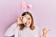 © Krakenimages.com - Young beautiful woman wearing cute easter bunny ears holding egg pointing thumb up to the side smiling happy with open mouth