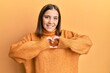 © Krakenimages.com - Young beautiful woman wearing turtleneck sweater smiling in love doing heart symbol shape with hands. romantic concept.
