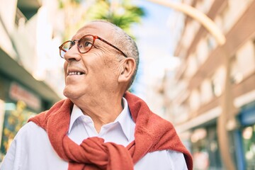 Wall Mural - senior man smiling happy wearing glasses walking at the city.