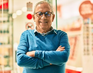 Wall Mural - senior grey-haired man with arms crossed smiling happy standing at the city.