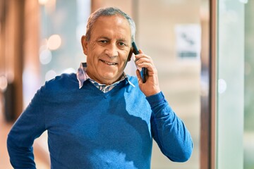 Wall Mural - senior grey-haired man smiling happy talking on the smartphone at the city.