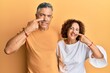 © Krakenimages.com - Beautiful middle age couple together wearing casual clothes pointing with hand finger to face and nose, smiling cheerful. beauty concept