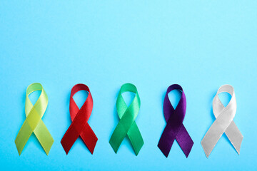 Wall Mural - Colorful ribbons on light blue background, flat lay with space for text. World Cancer Day