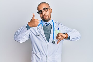 Poster - Hispanic adult man wearing doctor uniform and stethoscope doing thumbs up and down, disagreement and agreement expression. crazy conflict