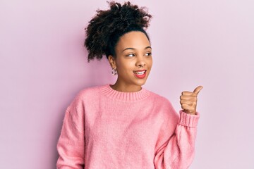 Wall Mural - Young african american girl wearing casual clothes pointing thumb up to the side smiling happy with open mouth