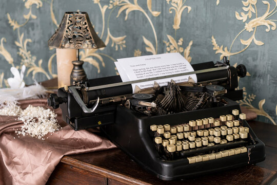 Vintage old style typewriter on the retro table. Retro interior with the old furniture and vintege mirror on the wall.