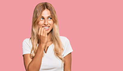 Canvas Print - Beautiful blonde young woman wearing casual white tshirt looking stressed and nervous with hands on mouth biting nails. anxiety problem.