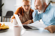 © Goran - Shocked senior couple reading their home finances on laptop