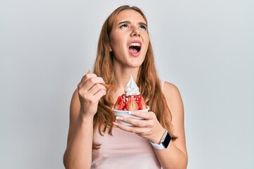 Poster - Young blonde woman eating strawberry ice cream angry and mad screaming frustrated and furious, shouting with anger looking up.