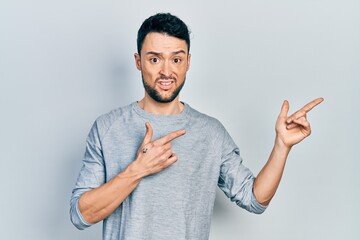 Poster - Young hispanic man pointing with fingers to the side clueless and confused expression. doubt concept.