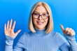 © Krakenimages.com - Young blonde woman wearing casual clothes and glasses showing and pointing up with fingers number six while smiling confident and happy.