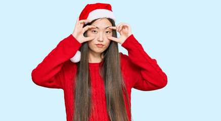 Sticker - Young chinese woman wearing christmas hat trying to open eyes with fingers, sleepy and tired for morning fatigue