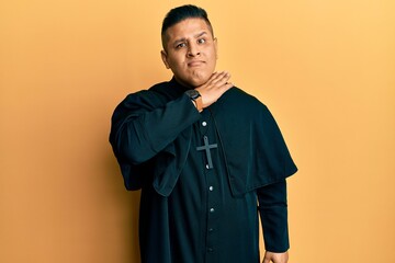 Canvas Print - Young latin priest man standing over yellow background cutting throat with hand as knife, threaten aggression with furious violence