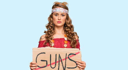 Poster - Young blonde girl wearing hippie style holding no guns warning banner thinking attitude and sober expression looking self confident