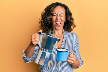 Poster - Middle age hispanic woman drinking italian coffee sticking tongue out happy with funny expression.