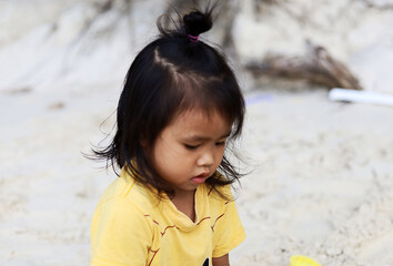 Beautiful Asia child girl have fun on sand the beach at Thailand.