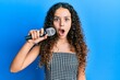 © Krakenimages.com - Teenager hispanic girl singing song using microphone scared and amazed with open mouth for surprise, disbelief face