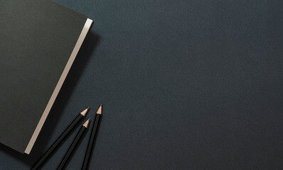 Mockup black cover book and pencil on black leather background.