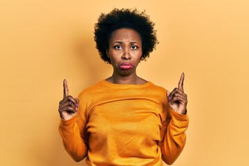 Wall Mural - Young african american woman wearing casual clothes pointing up looking sad and upset, indicating direction with fingers, unhappy and depressed.