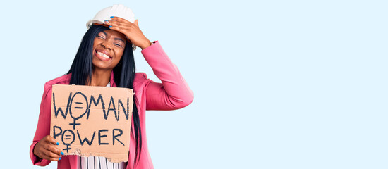 Poster - Young african american woman wearing architect helmet holding woman power banner stressed and frustrated with hand on head, surprised and angry face