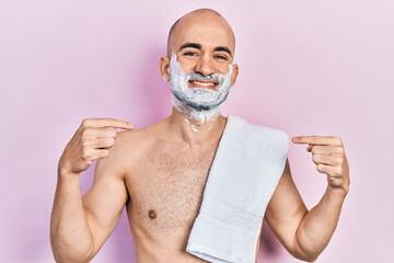 Sticker - Young bald man shirtless shaving beard with foam looking confident with smile on face, pointing oneself with fingers proud and happy.