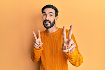 Young hispanic man wearing casual clothes smiling looking to the camera showing fingers doing victory sign. number two.