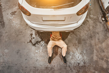 Wall Mural - Mechanic lying and working under car at the repair garage.