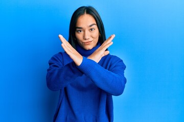 Wall Mural - Young asian woman wearing casual winter sweater rejection expression crossing arms doing negative sign, angry face