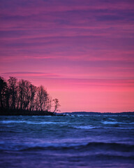 Wall Mural - Beautiful sunset full of colors with a dark sea in the foreground. Cape with trees enters from the left side