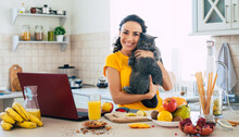 Cute Beautiful And Happy Young Brunette Woman With Her Cat In The Kitchen At Home Is Preparing Fruit Vegan Salad Or A Healthy Smoothie And Having Fun