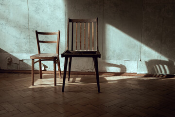 Two chairs in an abandoned room. Light rays and shadows on the wall. Beautiful abandoned interior. Light and shadow.