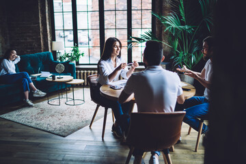 Positive coworkers gathering in workspace and brainstorming