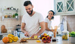 © My Ocean studio - Excited happy beautiful young couple in love cooking in the kitchen and having fun together while making fresh healthy fruits salad