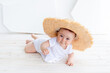 © Any Grant - a baby in a straw hat is lying in a bright room