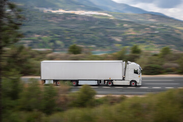 Wall Mural - Truck with refrigerated semi-trailer driving fast on the highway with the rest of the image in motion, creating a speed effect.