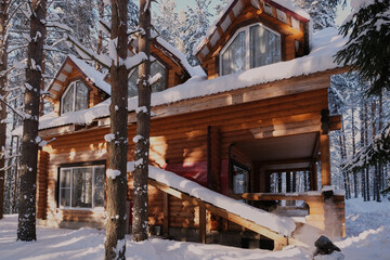 detached two-storey log cabin, with an attic, a beautiful house painted brown, surrounded by a winter coniferous forest, covered in snowdrifts