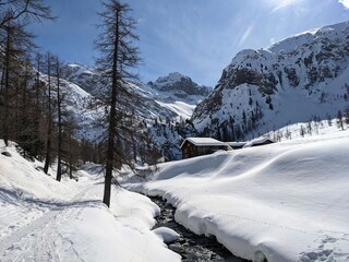 Breathtaking mountain landscape near the alp Sertig. Snow mountains with Sun, Snow a river and beautiful trees, Swiss