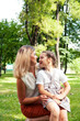 © iordani - young pretty mother walking with little cute daughter outside in green park, lifestyle poeple concept