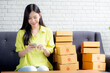 Young asian woman is entrepreneur check order from smartphone with customer while purchase online, logistic and delivery, online shopping, female is seller of business SME, merchant looking phone.