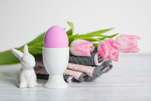 Side View Of  Porcelain Egg Cups With Pink Easter Egg And Porcelain Easter Bunnies And Same Pastel Colored Pink White Tulips.On A White Background .