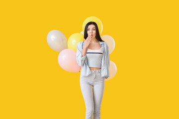 Poster - Surprised young woman with balloons on color background