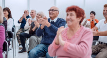 A Group Of Senior Citizens Applaud In The Conference Room