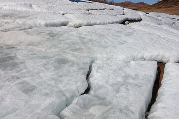 Snow in the mountains melts in the spring. Layers of snow descend in parts from the slope. Natural background.