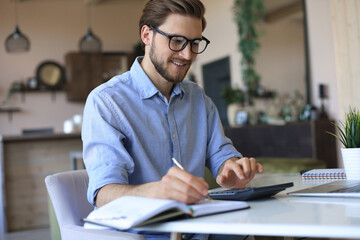 Sticker - Happy young business man is analizing financial documents from home during self isolation.