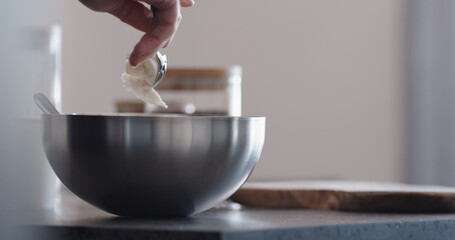 Man making granola add coconut butter into steel bowl on kitchen countertop